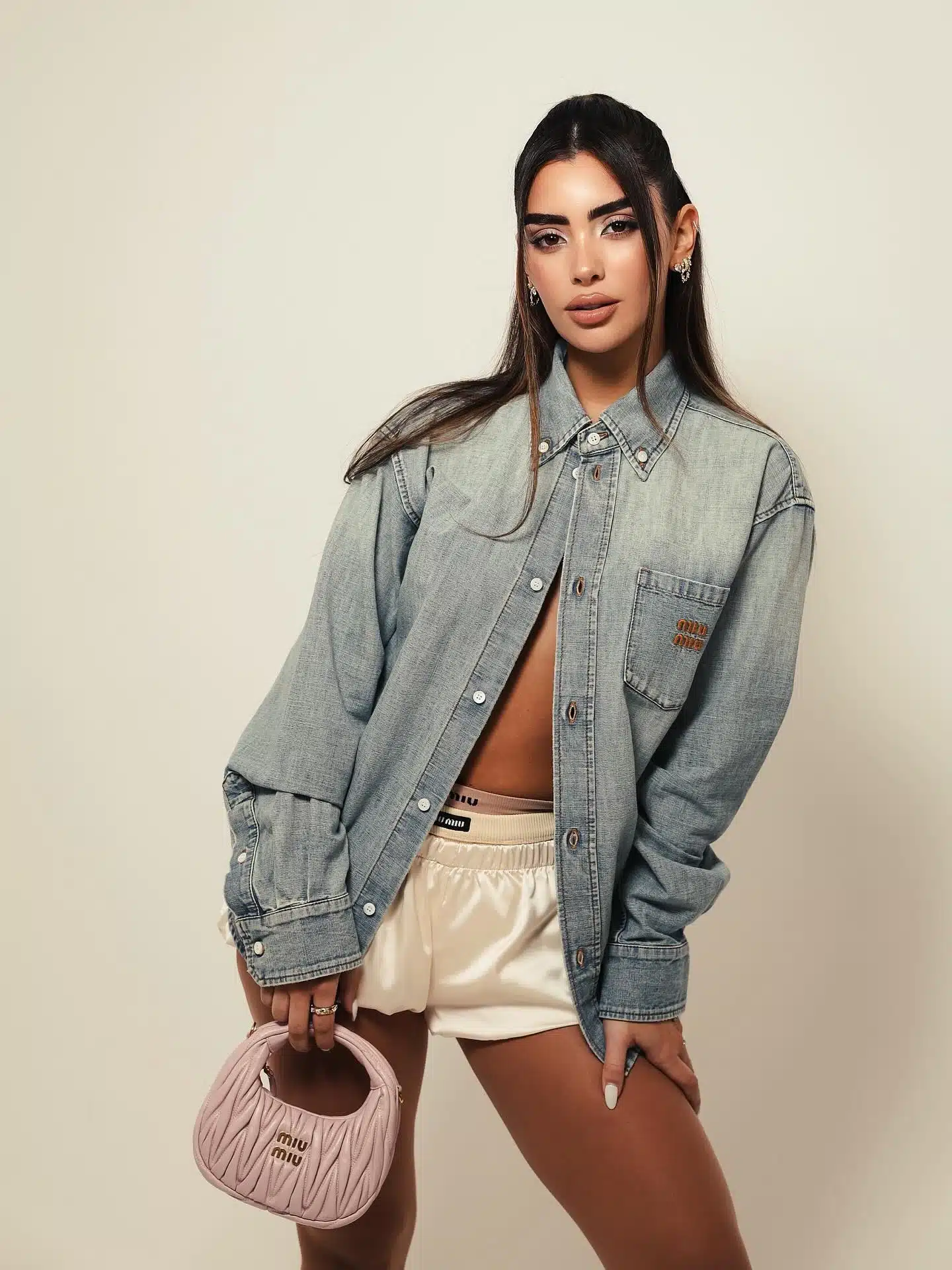 Close editorial frame of a pink leather handbag held by the model