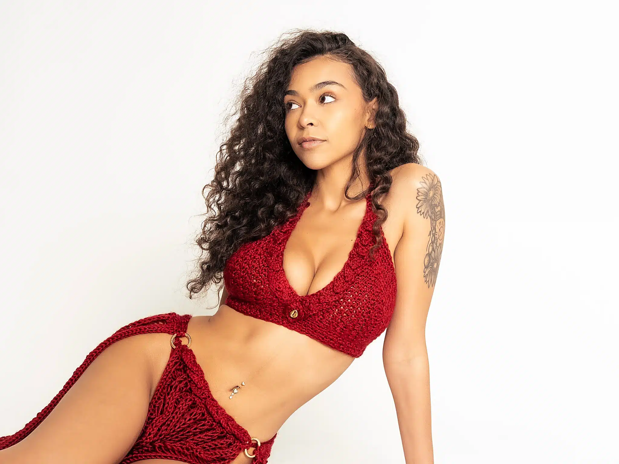 Woman in a red crochet bikini set reclining on the studio floor at a Miami photo studio