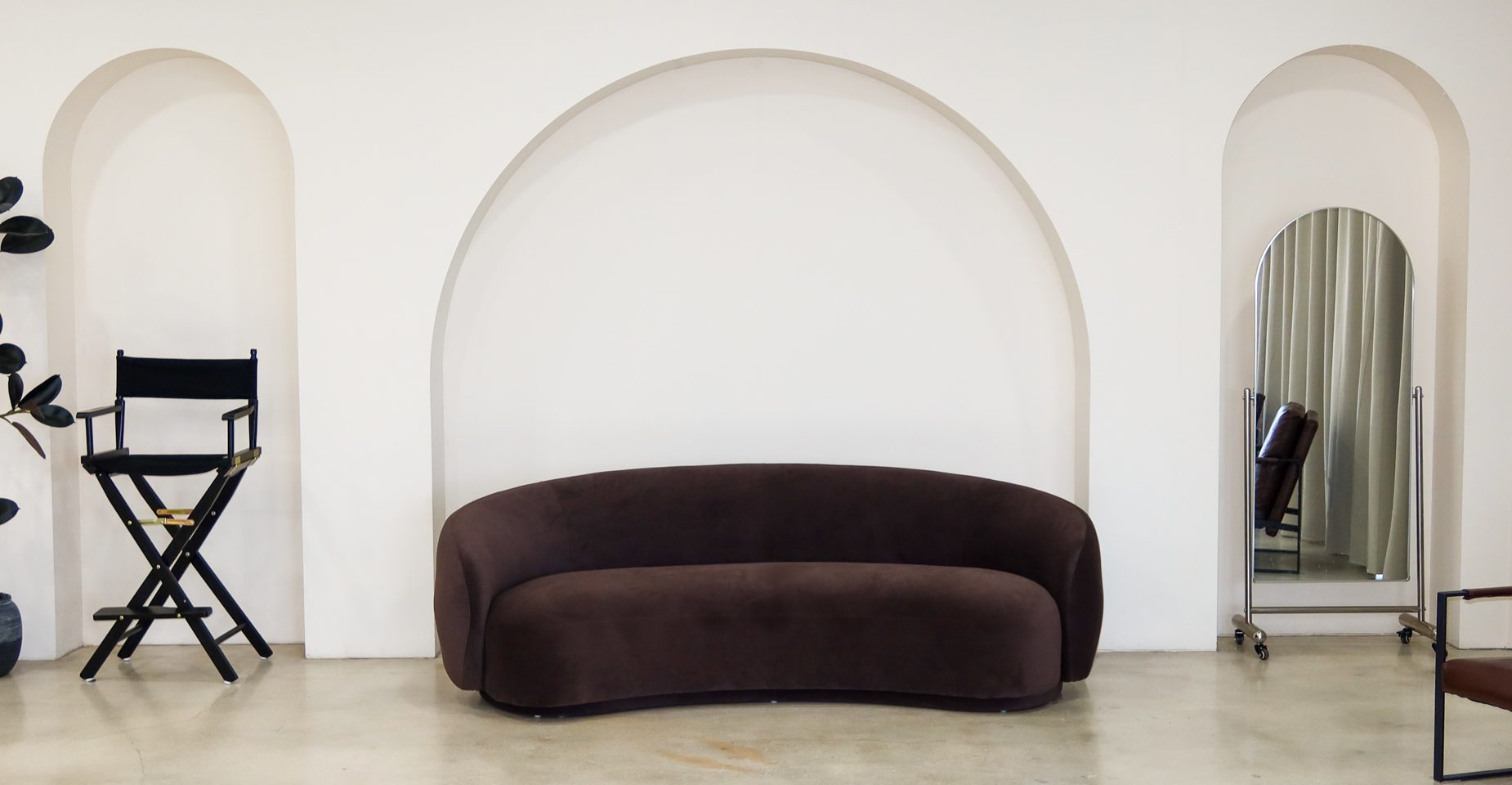 Curved brown sofa beneath the three-arch set at CC Studios Miami