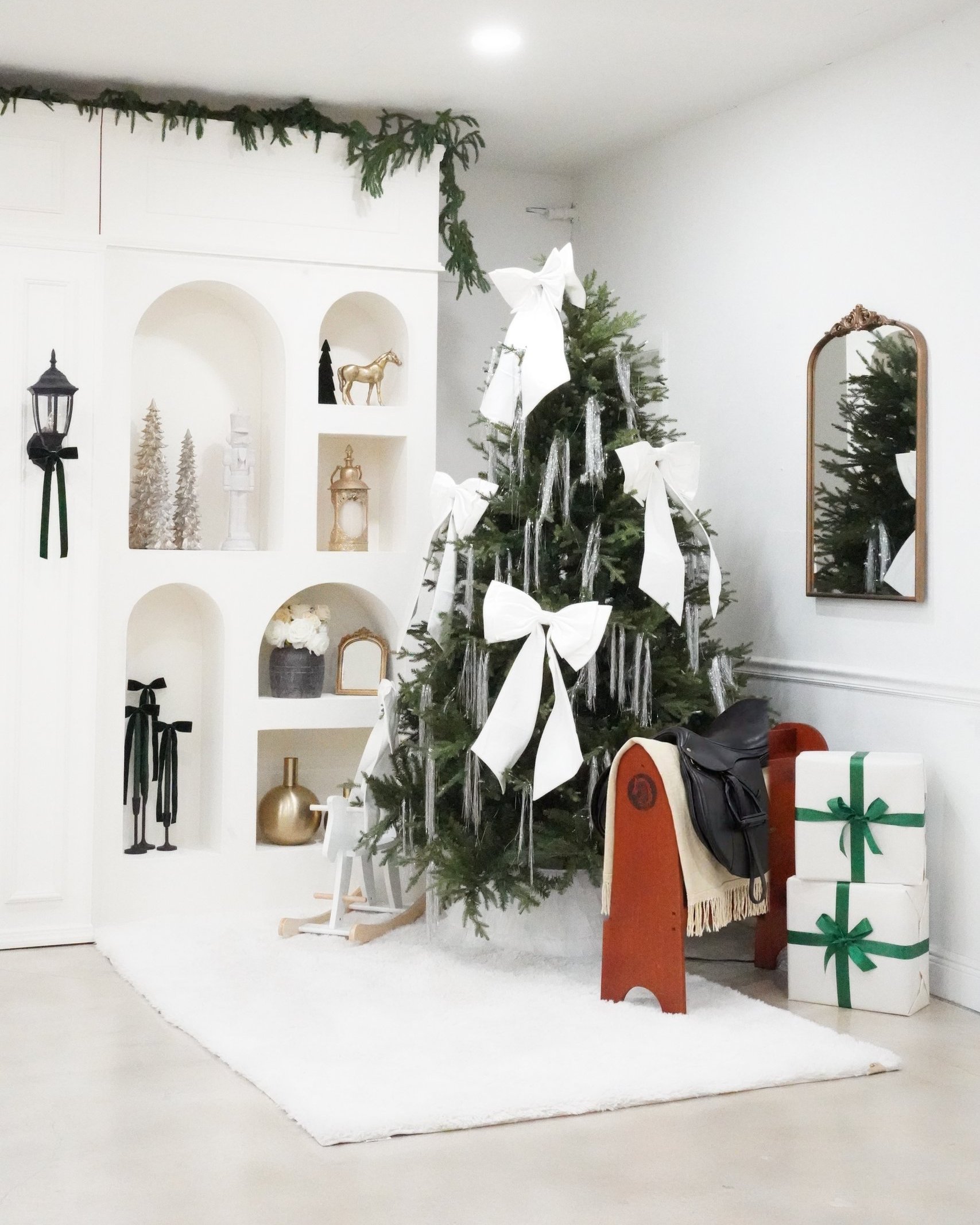 Christmas photo studio in Miami | Creative Canvas Photo Studio Miami Set de fotos navideñas en Miami árbol con lazos blancos junto a nichos en arco y una silla de montar