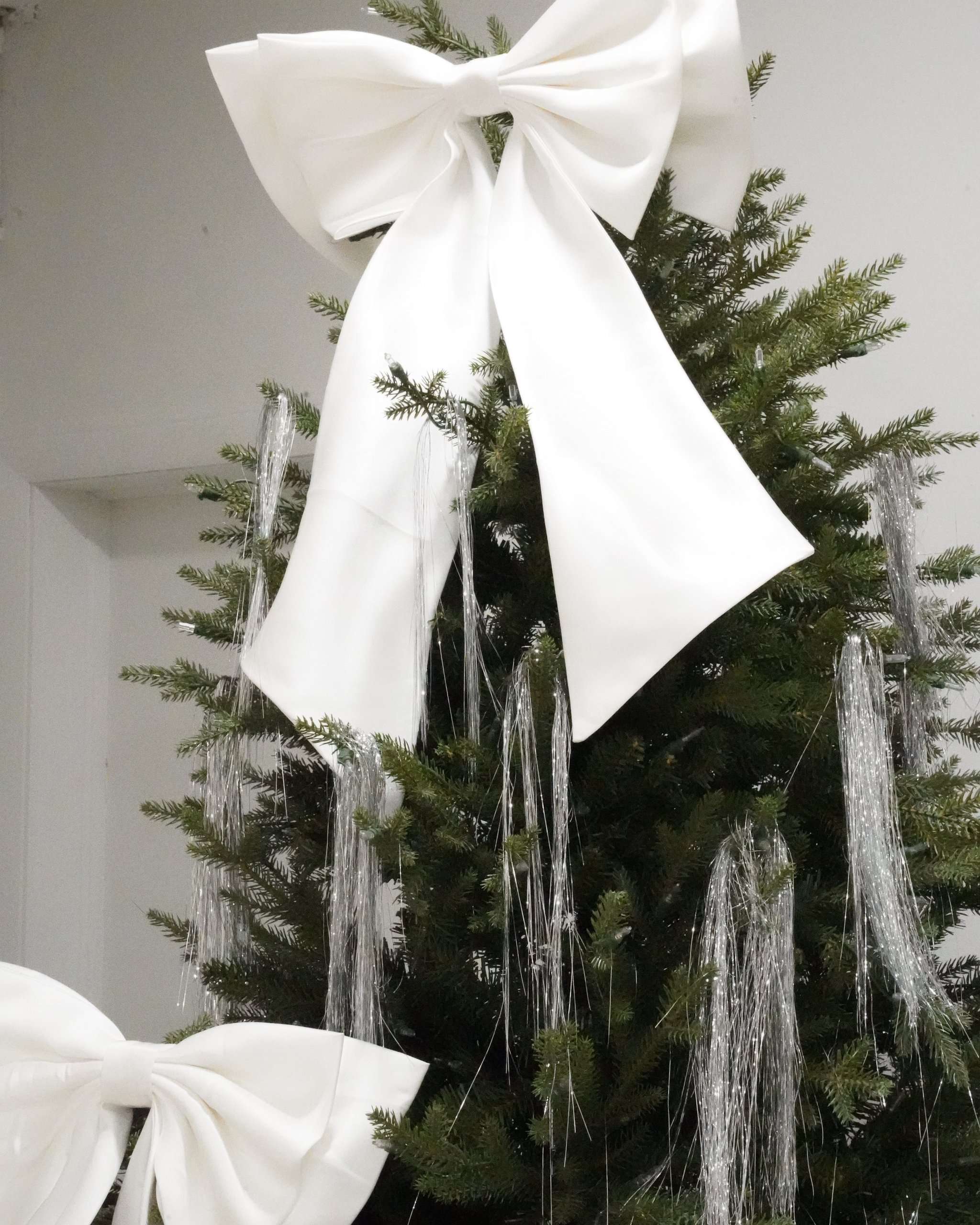 Christmas photo studio in Miami | Creative Canvas Photo Studio Miami Set de fotos navideñas en Miami árbol decorado con lazos blancos gigantes y oropel plateado
