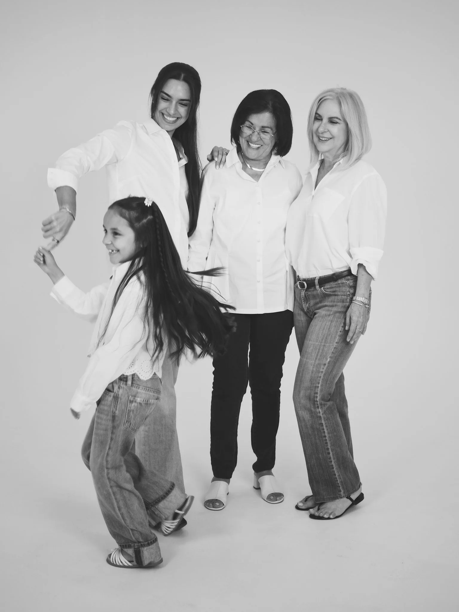 Black and White Family Portrait Miami Photo Studio | Twirl | Creative Canvas Photo Studio Miami Fotos familiares en blanco y negro en Miami niña girando de la mano de su mamá junto a dos mujeres de su familia