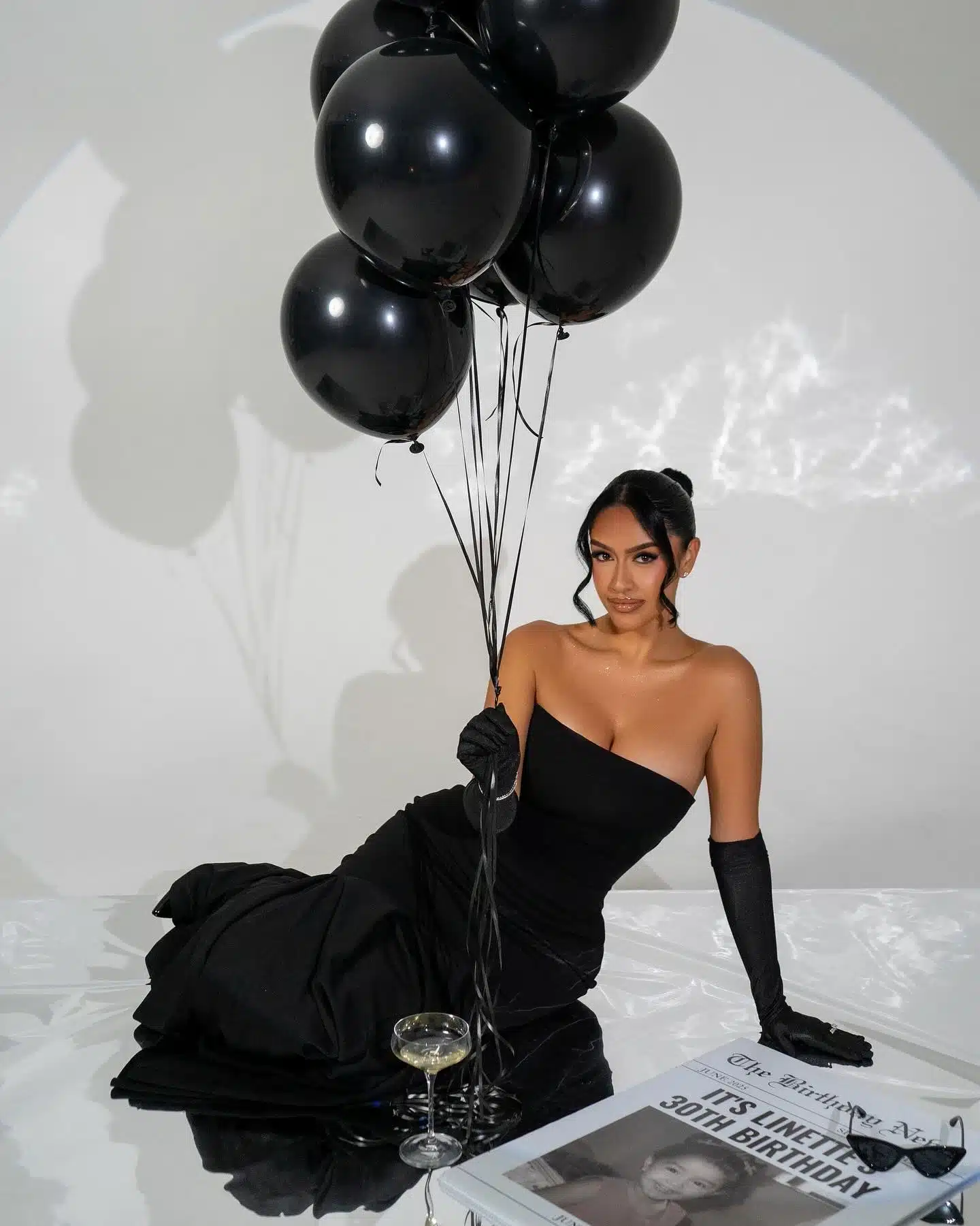 Black dress birthday photoshoot in Miami | Creative Canvas Photo Studio Miami Fotos de cumpleaños en Miami vestido negro recostada con globos negros y champán