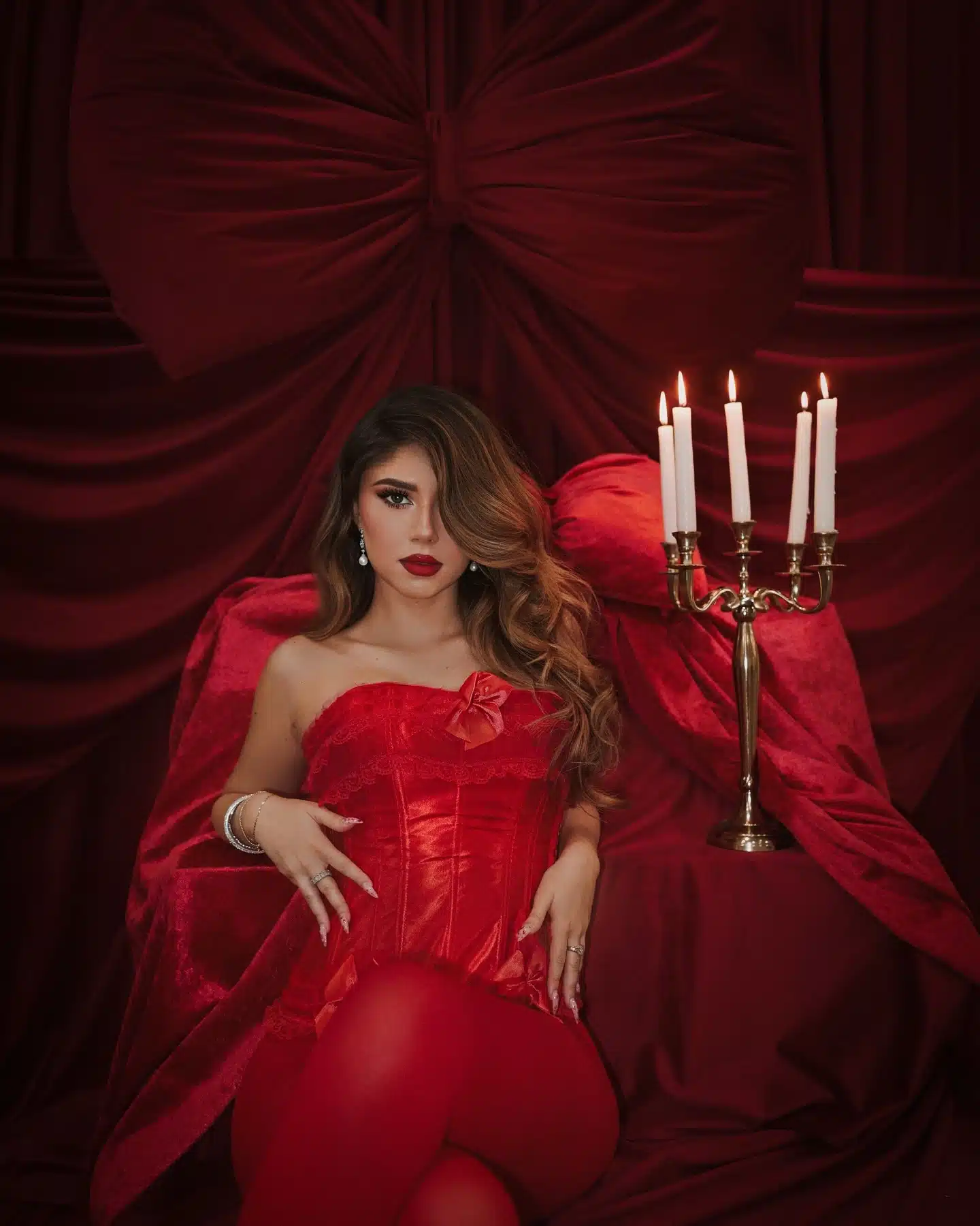 Editorial photoshoot at a Miami photo studio | Creative Canvas Photo Studio Miami Sesión de fotos de moda en Miami corsé de satén rojo junto a un candelabro en el set del moño rojo