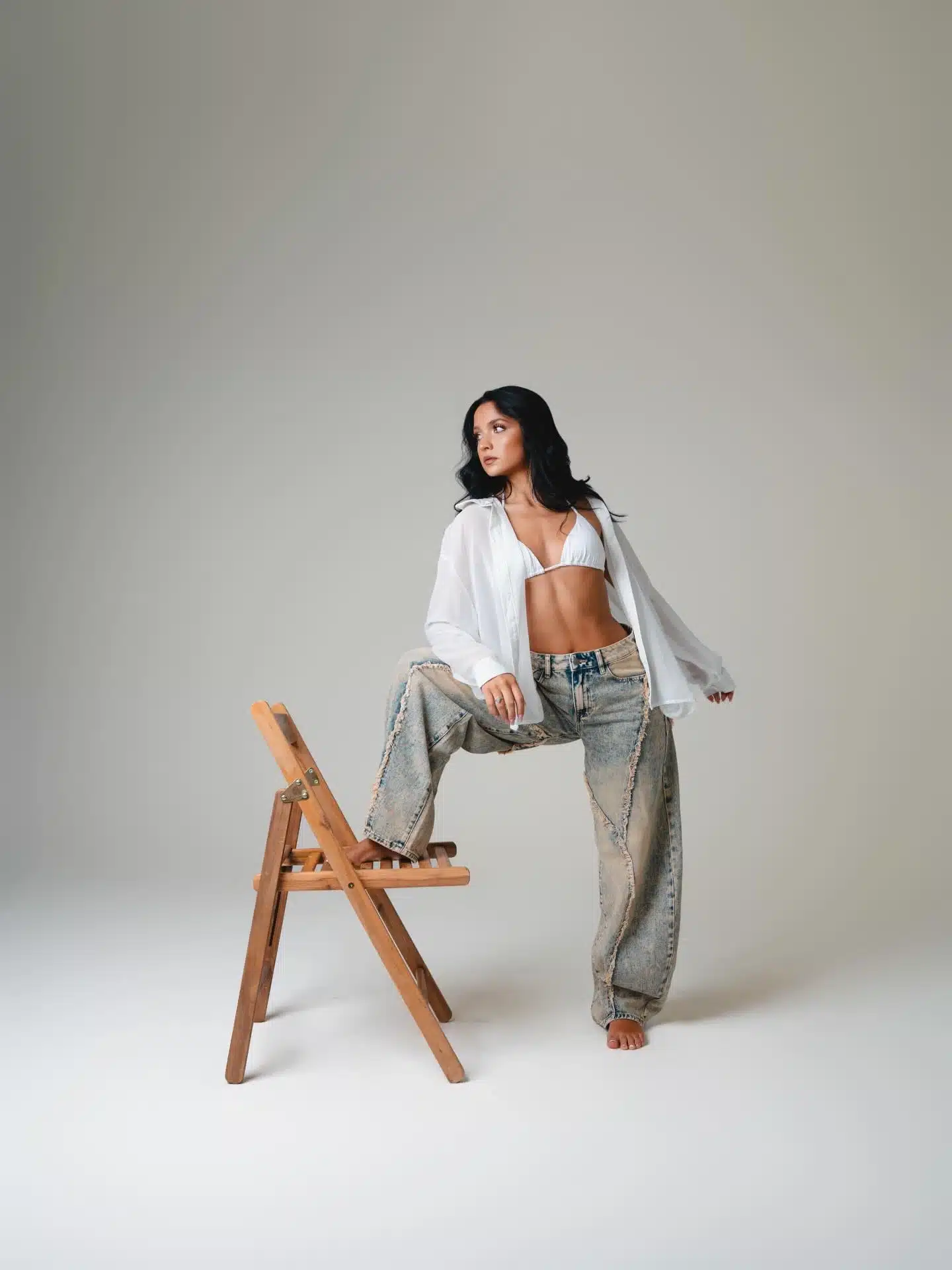 Editorial photoshoot in Miami | Creative Canvas Photo Studio Miami Moda editorial en Miami top blanco camisa abierta y jeans holgados con un pie en la silla