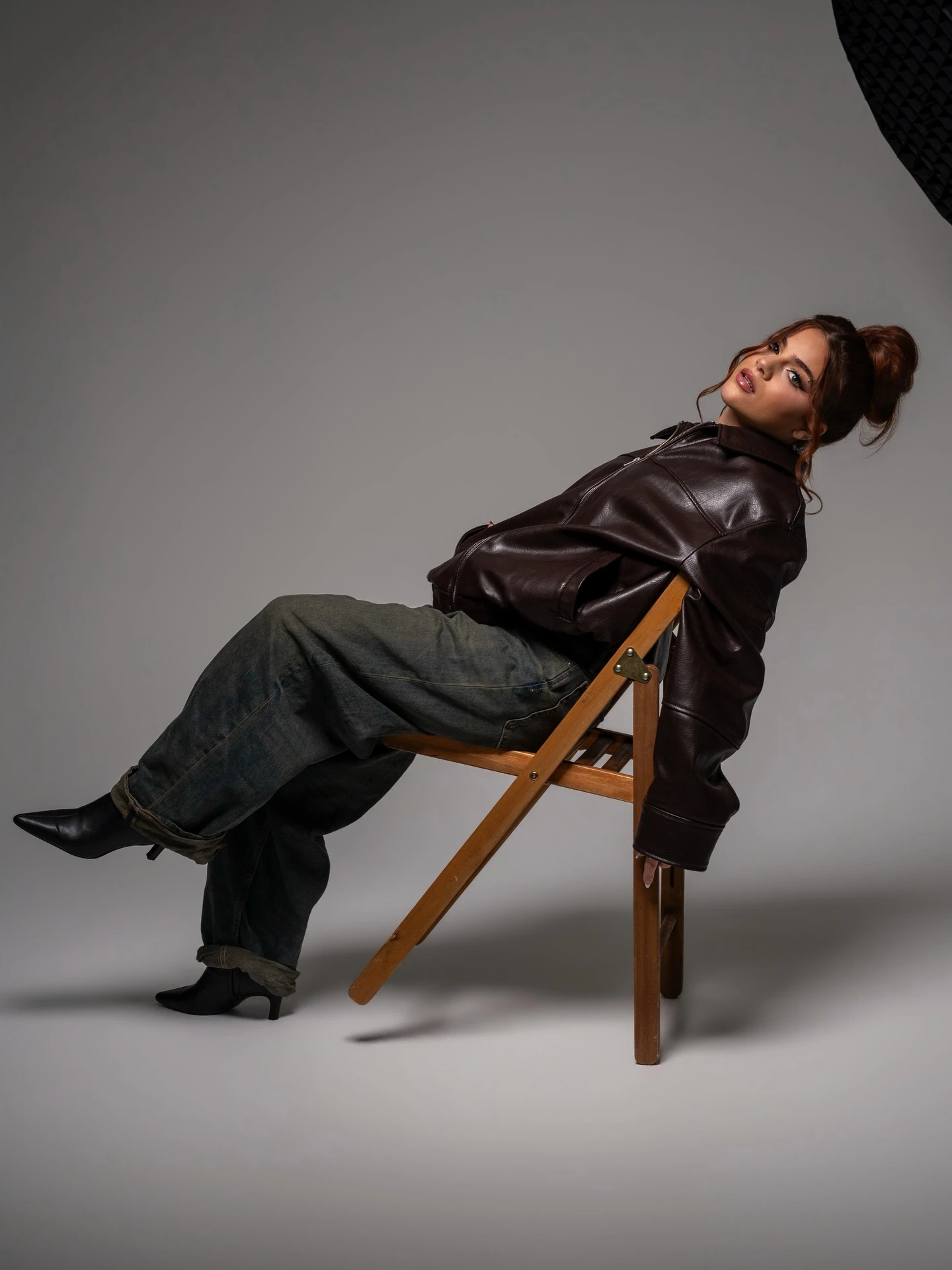 Miami fashion photographer | Creative Canvas Photo Studio Miami Moda editorial en Miami chaqueta de cuero marrón recostada en una silla plegable mirando atrás