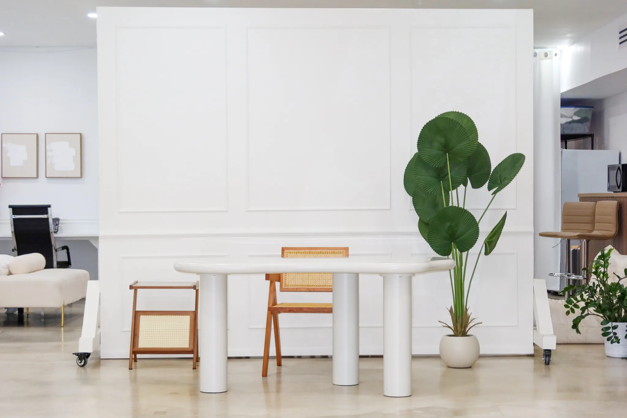 Photo studio in Miami | White Paneled Wall Set | Creative Canvas Photo Studio Miami Estudio fotográfico en Miami pared blanca con molduras mesa blanca sillas de rejilla y palmera