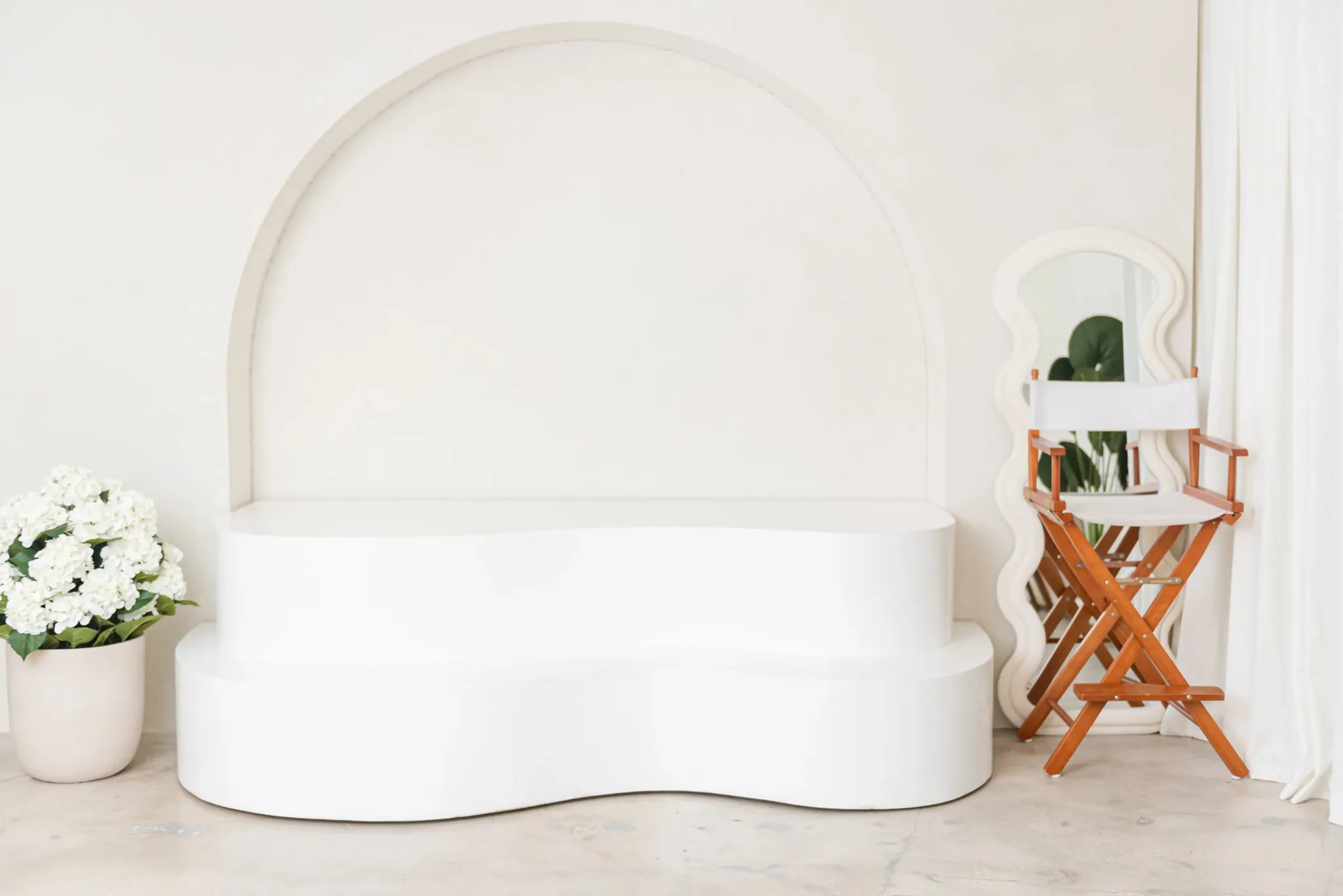 Photo studio rental in Miami | Creative Canvas Photo Studio Miami Estudio de fotografía en Miami sofá curvo blanco en un arco con flores y silla de director
